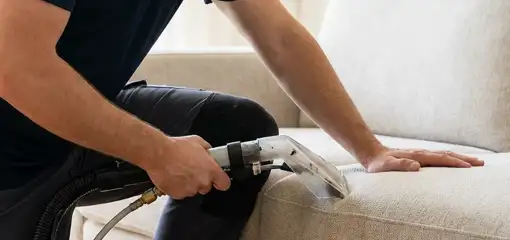 Professional upholstery cleaner deep-cleaning a fabric sofa with a handheld extraction tool, Charleston, SC.